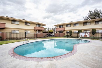 Apartments in Modesto CA - Dry Creek Apartments Gated Pool Lined With Brick And Concrete Surrounded By Grass
